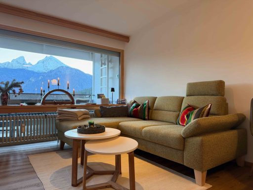 Fewo Gipfeltraum Sofa Gemütliches Wohnzimmer mit einem grünen Sofa, Tisch und Blick auf Berge.